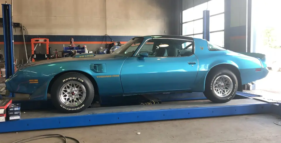 Blue Pontiac Trans Am 6.6 on the alignment rack inside the shop